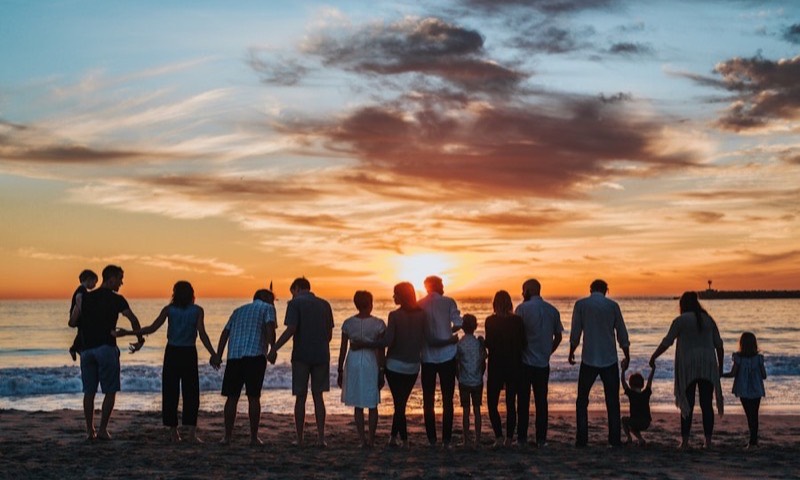 Three generations of a family together on a beach at sunset
