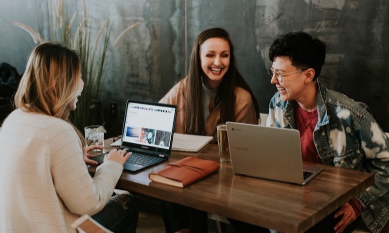 Friends completing an online form together on laptops