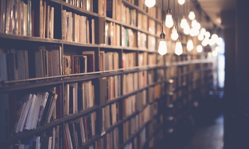 A long library aisle lit by hanging bulbs