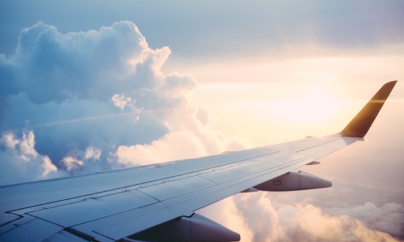 Aircraft wing above the clouds at sunset