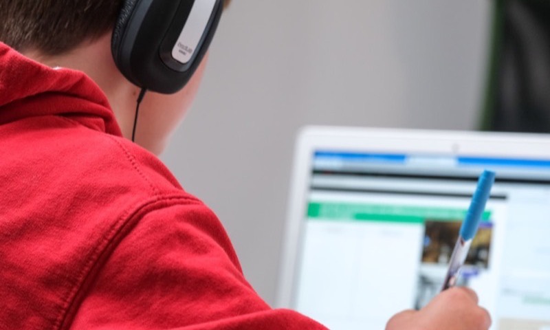 A child with headphones working through an online lesson